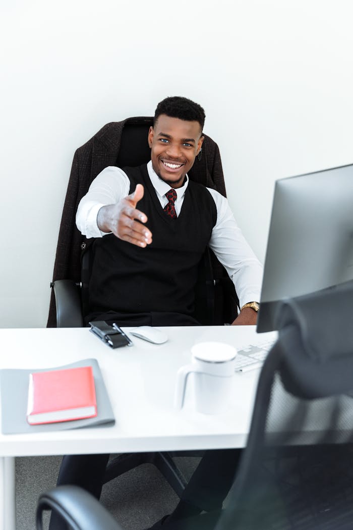Smiling professional man in an office extends a welcoming handshake.